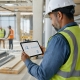 Contractor reviewing project hours and labor costs in time tracking software on a construction site